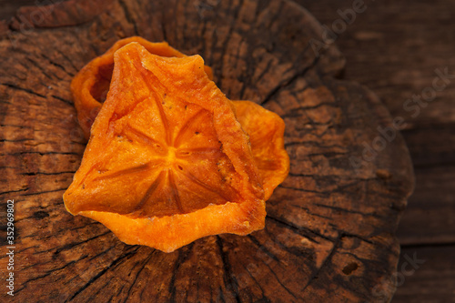 Bright orange slices of dried persimmon  Hoshigaki  on a textured wooden background. Closeup. View from above