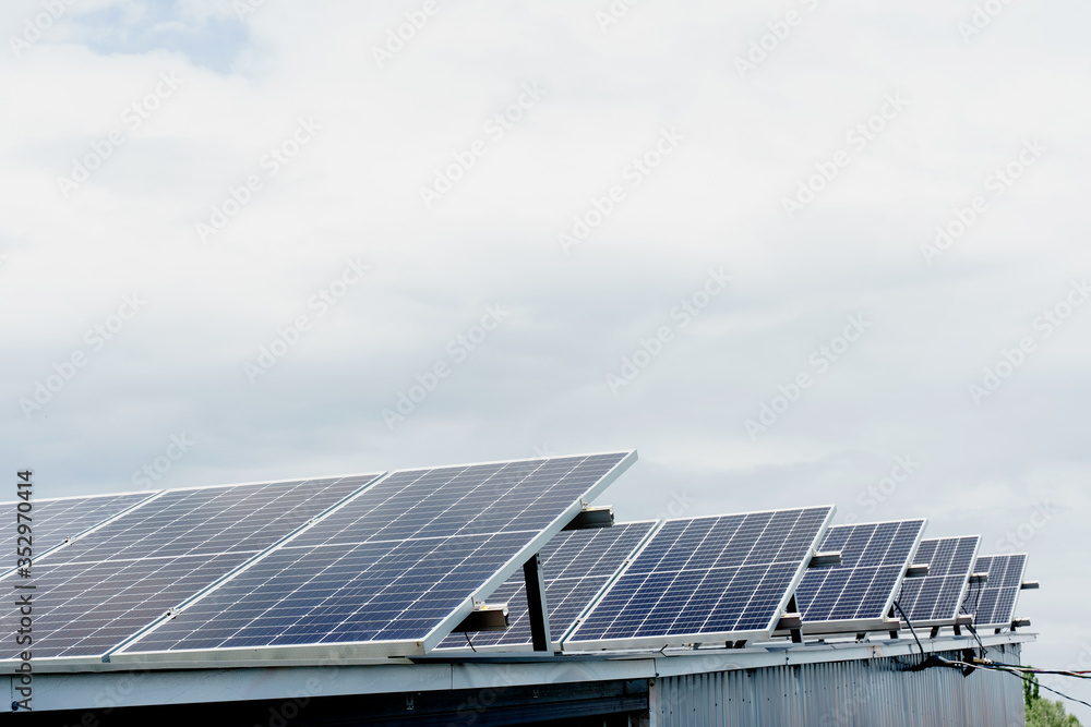 Solar panels stands in row on the roof . Free electricity for home. Sustainability of planet. Green energy. Solar cells power plant business. Ecological clean energy. Blue panels on the ground. Solar panels stands in row on the roof . Free electricity for home. Sustainability of planet. Green energy. Solar cells power plant business. Ecological clean energy. Blue panels on the ground.
