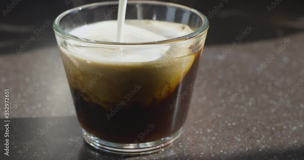In a coffee cup with black coffee, whipped cream is poured, cappuccino is made. Stone background. In a coffee cup with black coffee, whipped cream is poured, cappuccino is made. Stone background.