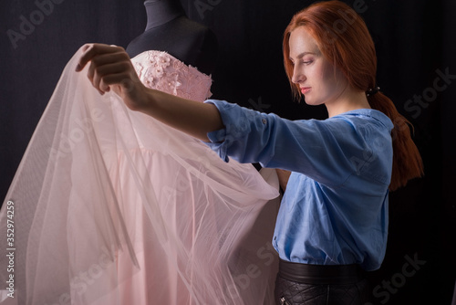 wedding delicate pink dress on a mannequin, in the manufacturing process. In a design studio. A professional master couturier designer examines his work after manufacture.