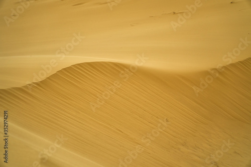 The texture of the sand. Waves of sand-hills. Desert and patterns. The Wallpaper is yellow and orange. © Vladimir