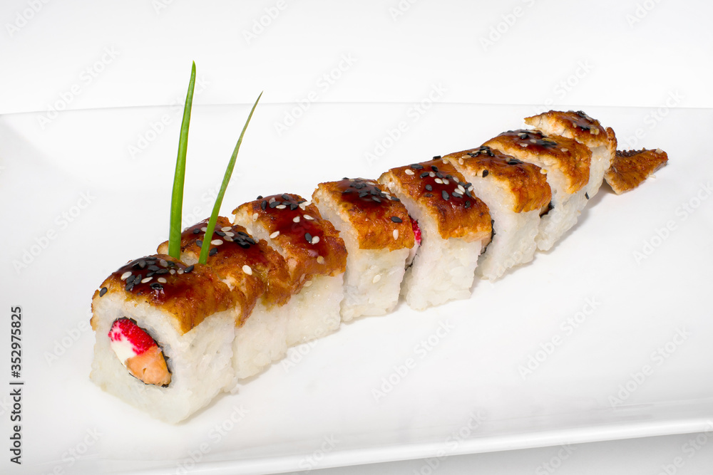 Japanese roll in the form of a dragon made of rice cream cheese, salmon, eel, sesame, unagi sauce on a white plate on a white plate Japanese roll in the form of a dragon made of rice cream cheese, salmon, eel, sesame, unagi sauce on a white plate on a white plate