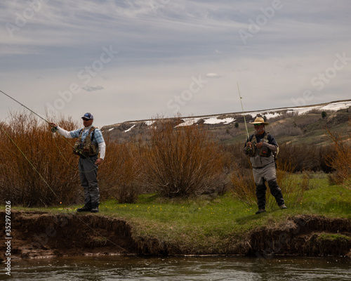 A man teaching a boy how to fly fish on a western trout stream.