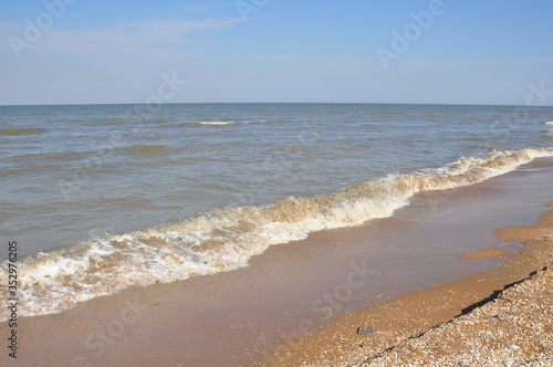 Sandy seashore with foamy wave of surf and clear sky  