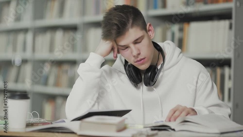 Tired guy falls asleep while preparing for examination at school library