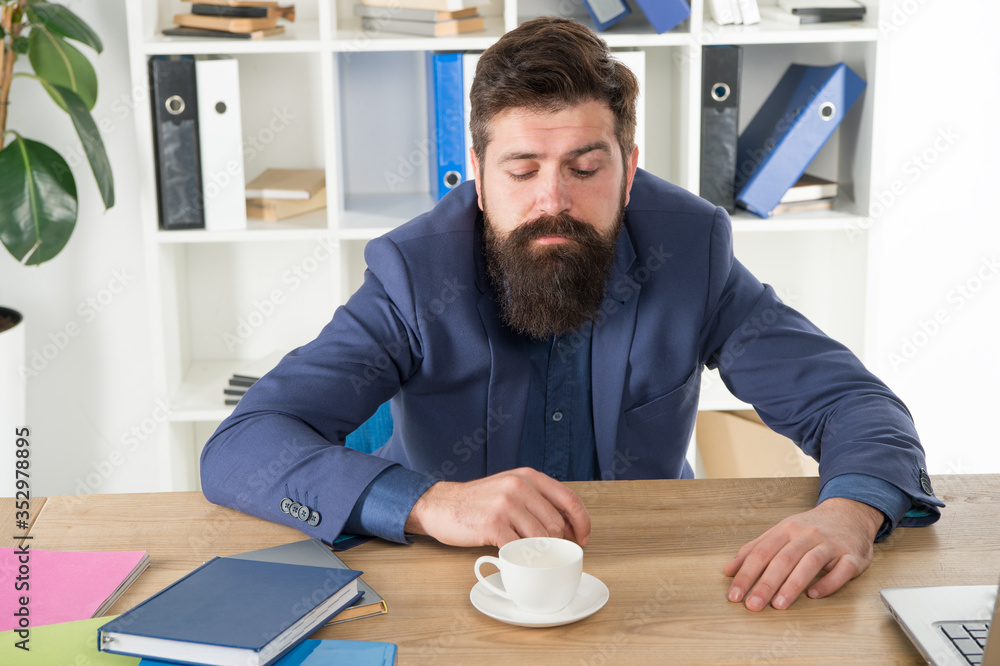 have no mood. need more energy. early morning drink. modern office life. mature businessman at workplace. exhausted and overworked. ceo sit at table with notebook and laptop. tired man drink coffee