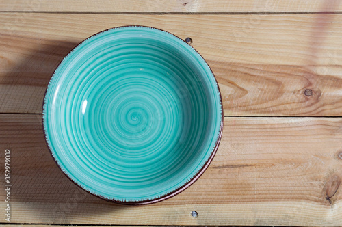 Flat lay close up of a ceramic turquoise spiral soup plate on a wooden background