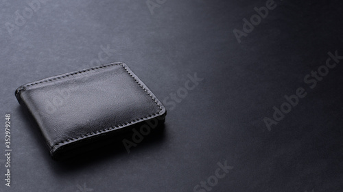 Black leather wallet on black texture background, desk from top view, copy space. 