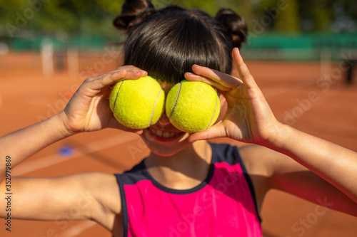 une petit fille s'amusant avec deux balles de tennis © kevin