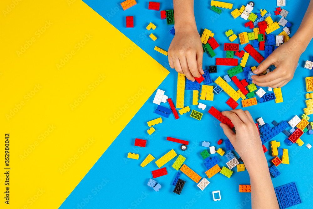 Fototapeta premium Vilnius, Lithuania - February 23, 2019. Children hands play with colorful lego blocks on the table