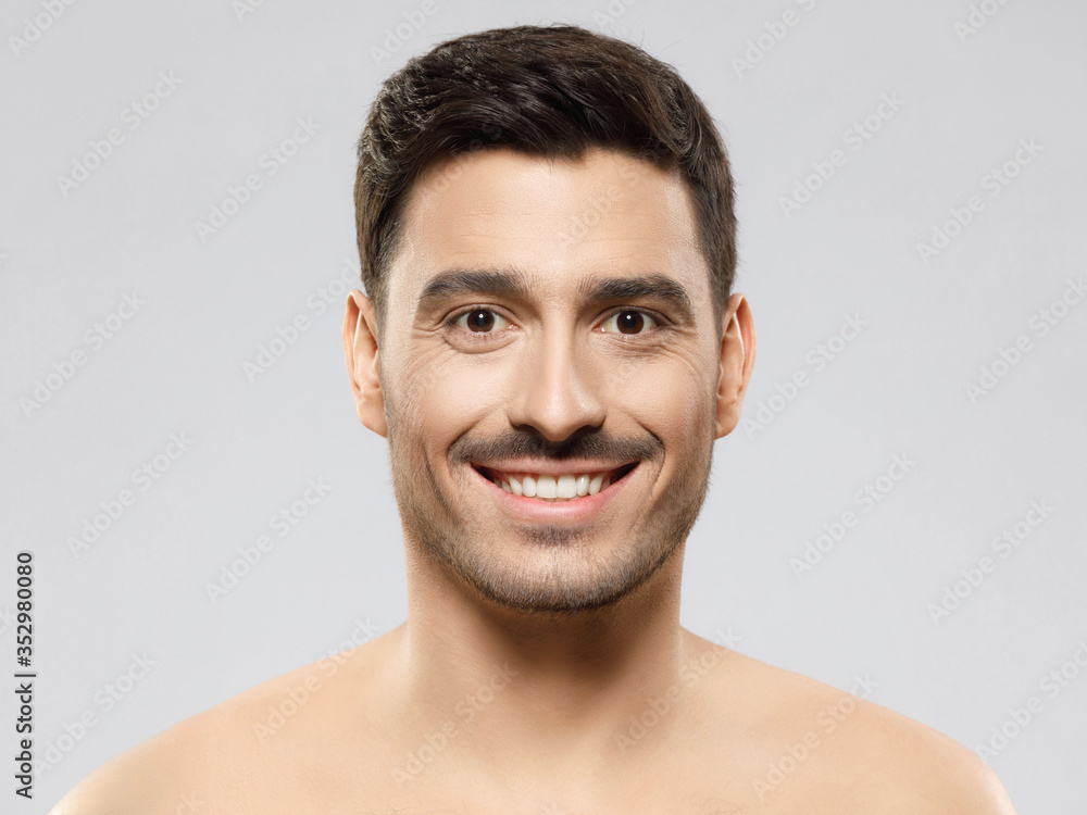 Obraz premium Portrait of young handsome guy standing with happy smile without shirt with healthy skin, concept of male beauty, isolated on gray background