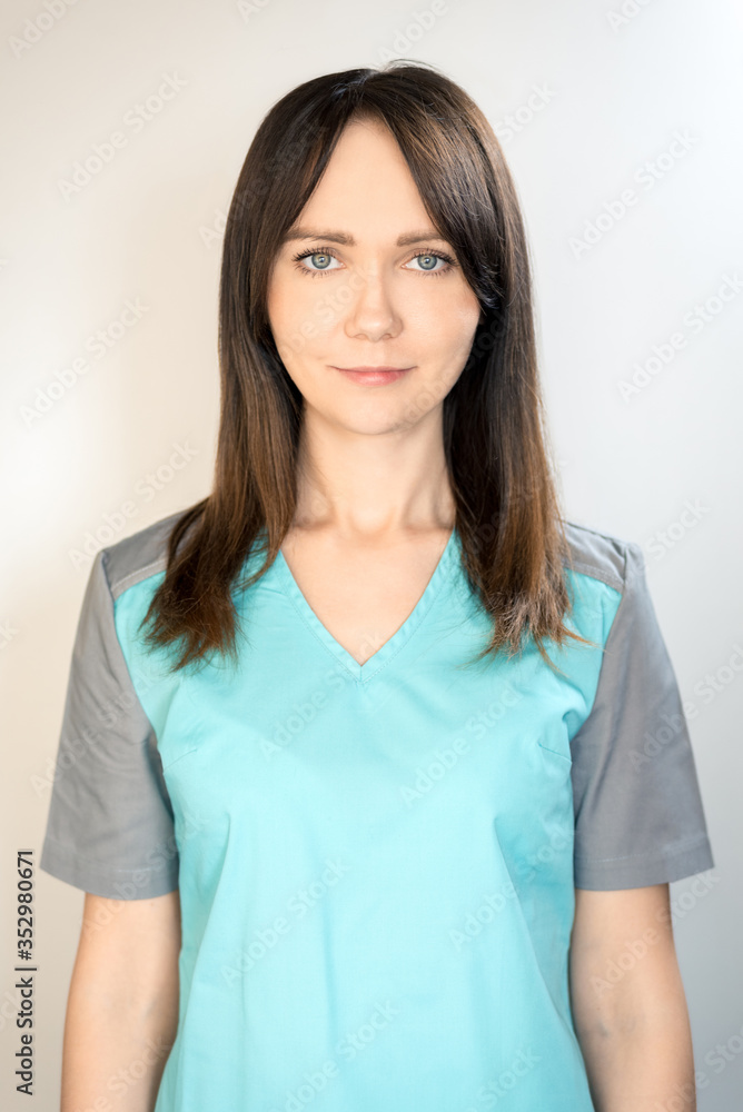 Young woman doctor with dark hair in a blue medical coat, smiling. Vertical frame Young woman doctor with dark hair in a blue medical coat, smiling. Vertical frame