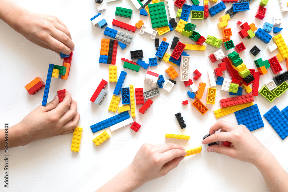 Naklejka premium Vilnius, Lithuania - April, 2017. Children hands play with colorful lego blocks on white table.