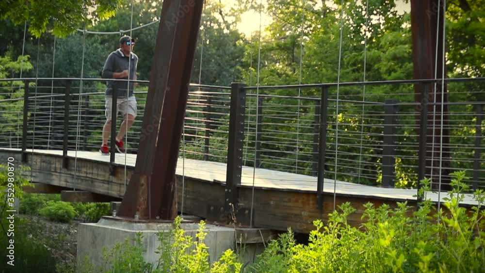 Man Running Across a Bridge in the Woods in Slow Motion Man Running Across a Bridge in the Woods in Slow Motion