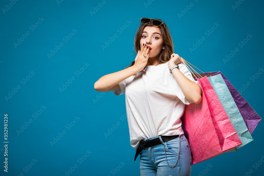 Young stylish beautiful girl in sunglasses is walking with multi-colored shopping bags. Concept shopping and store Young stylish beautiful girl in sunglasses is walking with multi-colored shopping bags. Concept shopping and store
