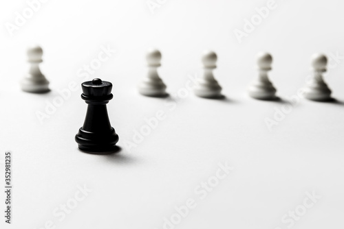Chess black rook stands against white pawns. Symbol of leadership and confrontation. Horizontal frame