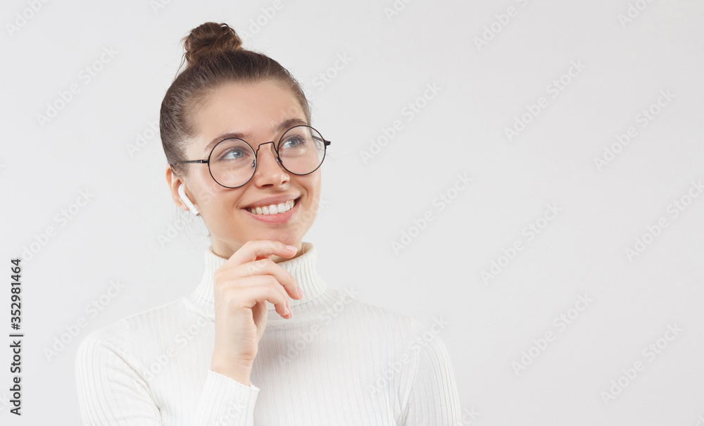 Horizontal banner of young woman in white sweater and eyeglasses, looking aside, thinking of new opportunities with smile, isolated on gray background with copy space Horizontal banner of young woman in white sweater and eyeglasses, looking aside, thinking of new opportunities with smile, isolated on gray background with copy space