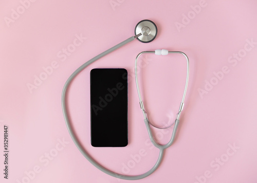 Online doctor consultation, concept with a stethoscope. Mobile application to keep in touch with the doctor online anytime top view with place for text.