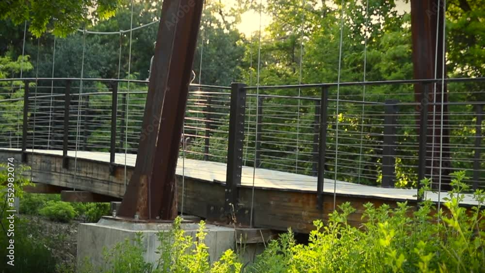 Man Running Away from Camera Across a Bridge in the Woods in Slow Motion Man Running Away from Camera Across a Bridge in the Woods in Slow Motion