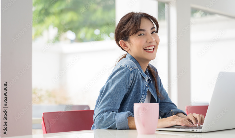 Asian girl working at a coffee shop with a laptop Woman happy smiling Asian girl working at a coffee shop with a laptop Woman happy smiling