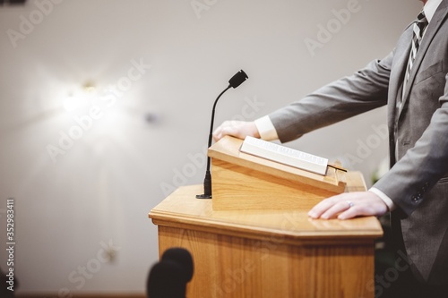 Valokuva Male in a formal outfit preaching the Holy Bible from the tribune at the altar o