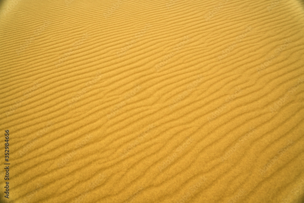 The texture of the sand. Waves of sand-hills. Desert and patterns. The Wallpaper is yellow and orange. The texture of the sand. Waves of sand-hills. Desert and patterns. The Wallpaper is yellow and orange.