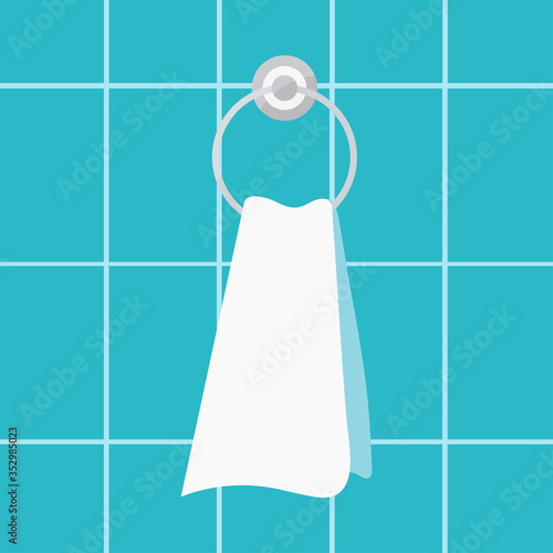 Towel with ring shaped holder on bathroom tile wall background.