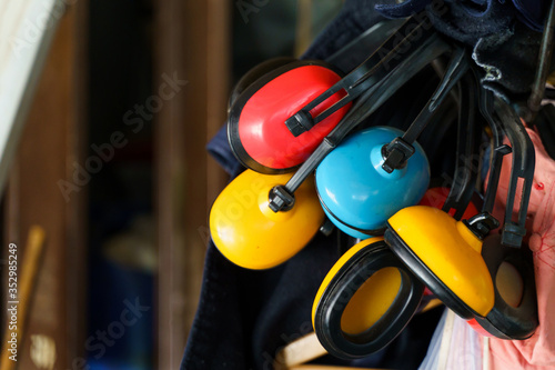 Foto Red yellow and blue ear muffs hanging in storage basement or room in day close u