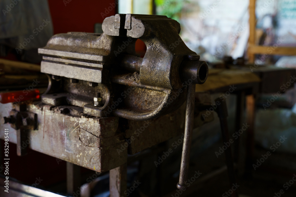 Old rusty steel clamp vise iron metal tool in the workshop workbench in day Old rusty steel clamp vise iron metal tool in the workshop workbench in day