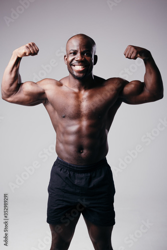 Portrait of a fitness trainer on gray background. Man shows biceps and smiles on a gray background