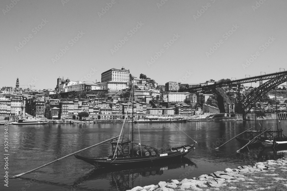 The iconic Rabelo Boats, the traditional Port Wine transports, with the Ribeira District and the Dom Luis I Bridge over the Douro River, Porto, Portugal. UNESCO World Heritage Site.