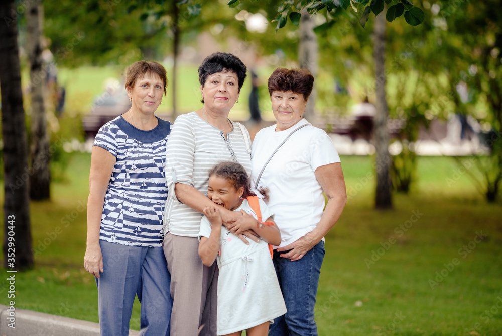 Mature Female Friends and little girl Socializing In Backyard Together. Mature Female Friends and little girl Socializing In Backyard Together.