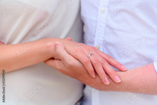 Man and woman newlyweds hold hands close-up.