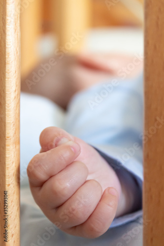 Baby hand through the wooden crib bars