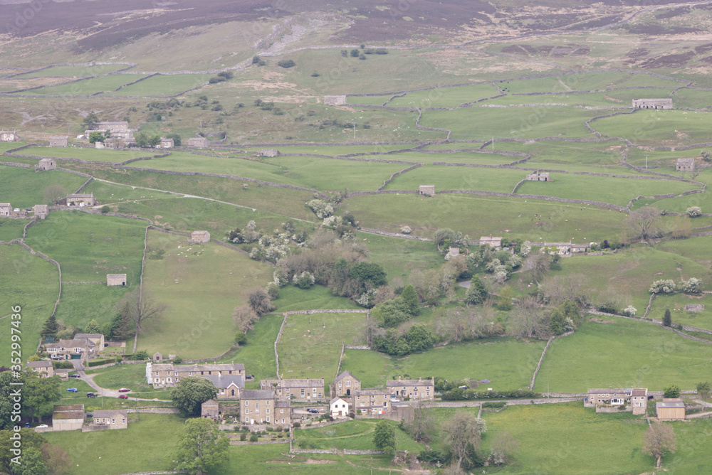 a Yorkshire Dales village with hills and fields surrounded by rock walls