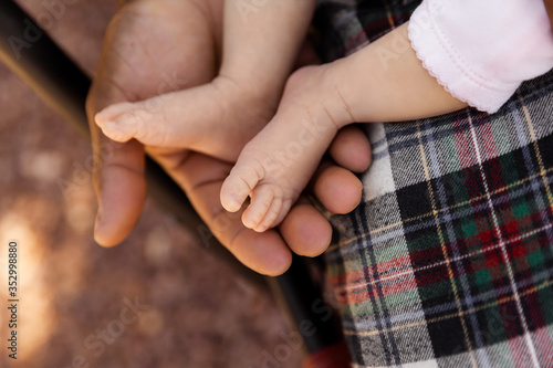 Father holding newborn daugther feet at summer sunset, family and parents concept