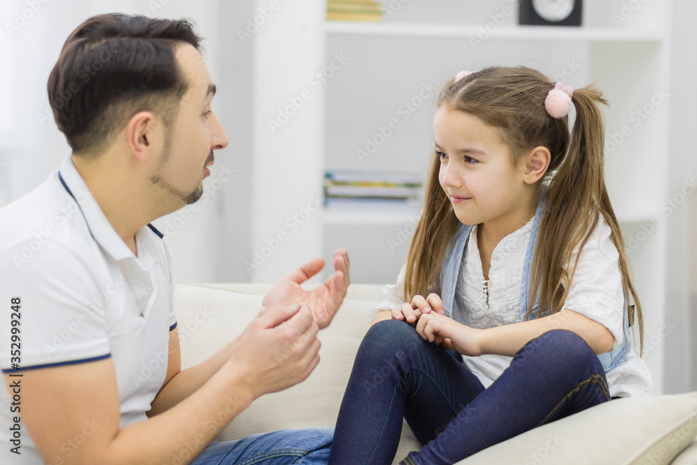 Father and daughter sitting on the sofa and having conversation. Father and daughter sitting on the sofa and having conversation.