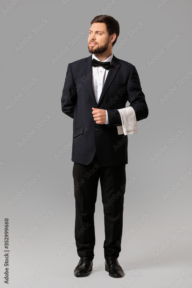 Handsome male waiter on grey background Handsome male waiter on grey background