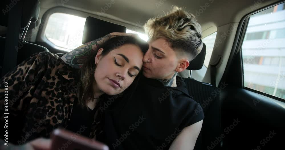 Lesbian couple embracing taking a selfie inside a taxi Lesbian couple embracing taking a selfie inside a taxi