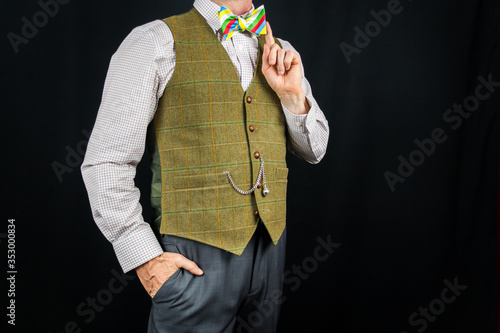 Portrait of Stylish Man in Tweed Waistcoat and Colorful Bow Tie. Stylish Model Showing Off Bow Tie. Copy Space of Sartorial Splendor. Elegant Gentleman.