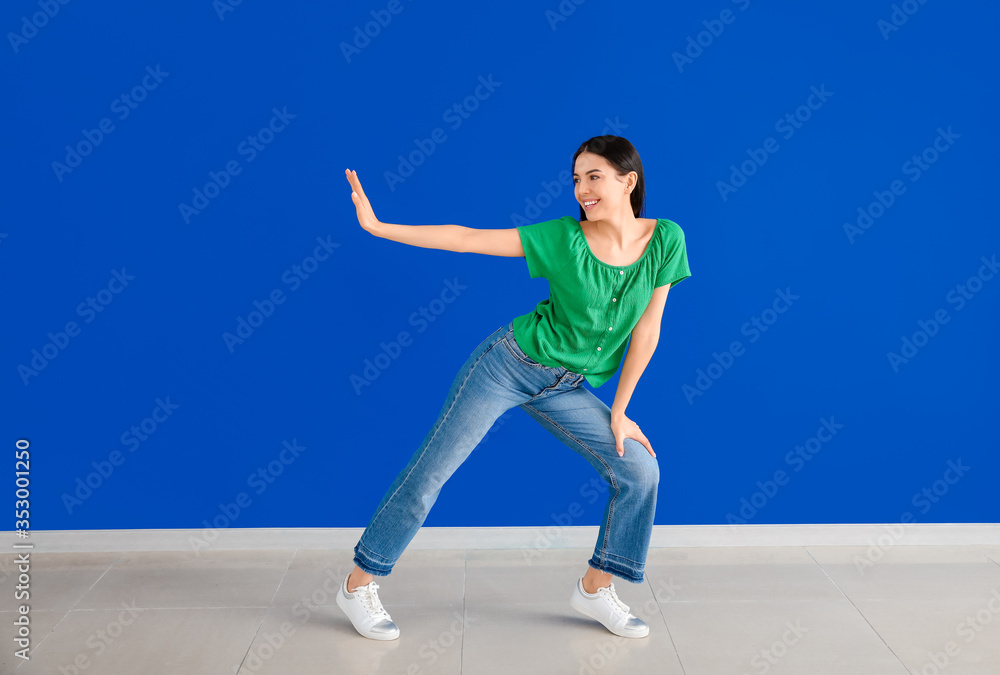 Beautiful young woman dancing against color wall Beautiful young woman dancing against color wall