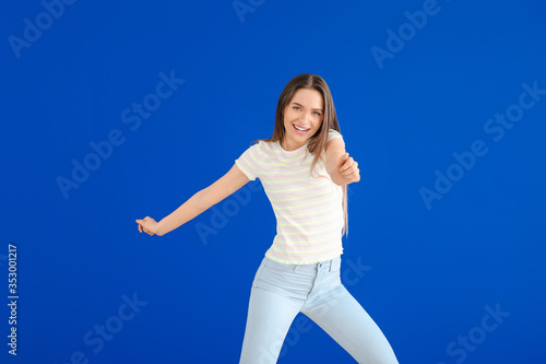 Fototapeta Naklejka Na Ścianę i Meble -  Beautiful young woman dancing against color wall