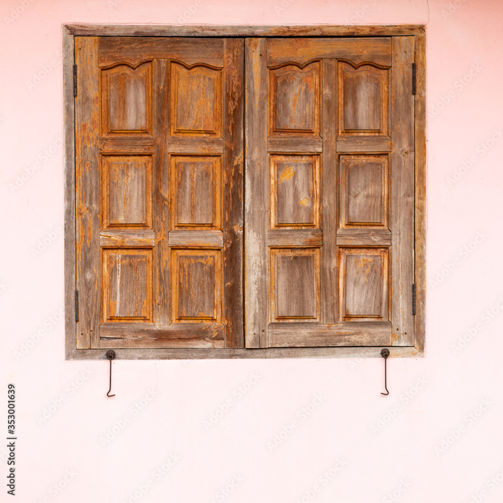 Old wooden windows with pink concrete walls.
