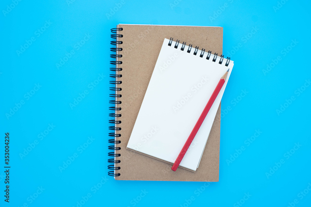 Top view above of open blank spiral notebook and red pencil isolated on light blue background for design mockup. Education and business concept. flat lay Top view above of open blank spiral notebook and red pencil isolated on light blue background for design mockup. Education and business concept. flat lay