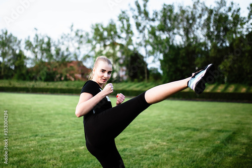 Healthy sports lifestyle. Athletic young woman in a sports dress doing fitness exercises. Fitness woman at the stadium. Young woman practicing karate on the street. Straight leg. Karate. Struggle.