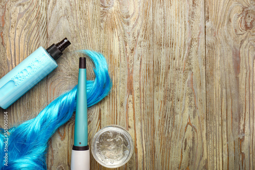 Hair spray with curler and strand on wooden background