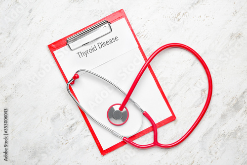 Clipboard with text THYROID DISEASE and stethoscope on white background photo