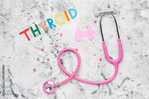 Text THYROID with pills and stethoscope on white background