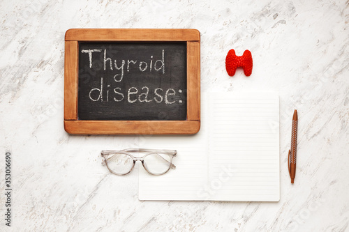 Chalkboard with text THYROID DISEASE and notebook on white background photo