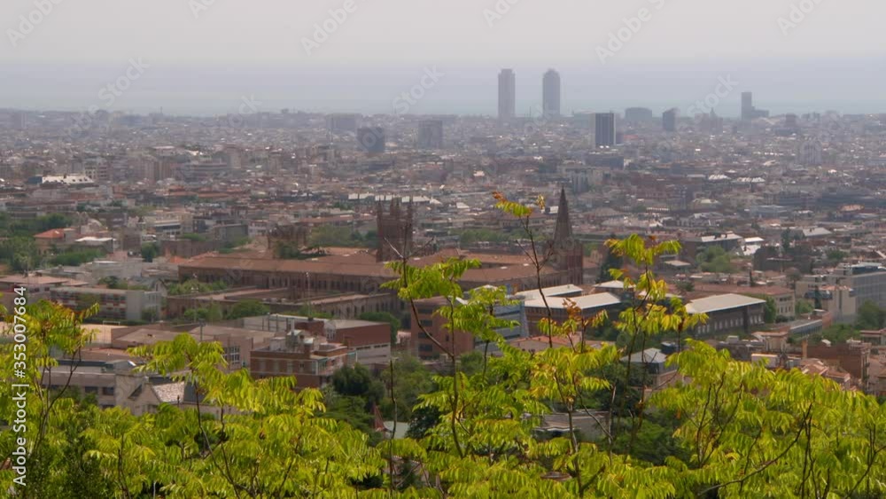 Aerial lockdown shot of trees against buildings in city on sunny day - Barcelona, Spain Aerial lockdown shot of trees against buildings in city on sunny day - Barcelona, Spain